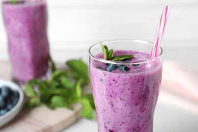 Photo of Glass of tasty blueberry smoothie on table, closeup