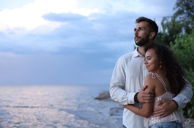 Lovely couple spending time together near river at sunset