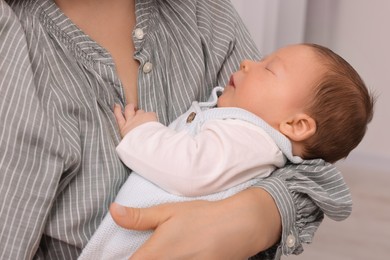 Mother holding her cute newborn baby on blurred background, closeup