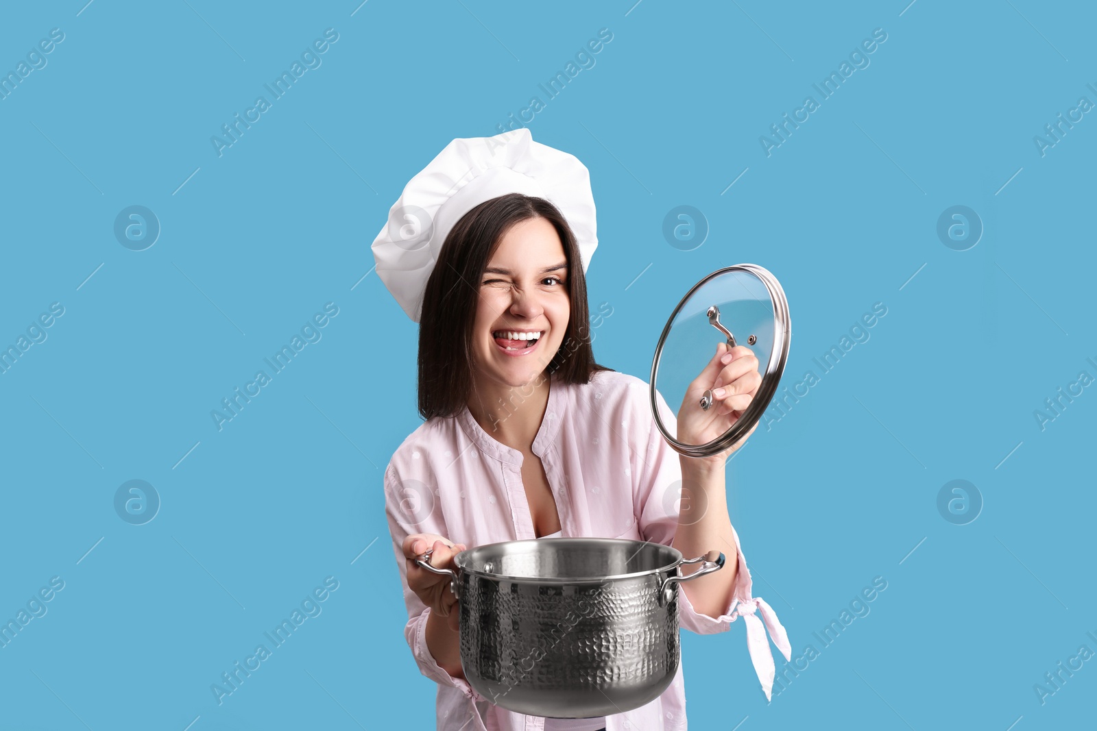 Photo of Happy young woman with cooking pot on light blue background