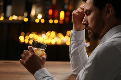 Photo of Man with glass of whiskey against blurred lights, closeup