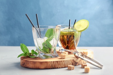 Glasses with delicious mint julep cocktail and ice on wooden board