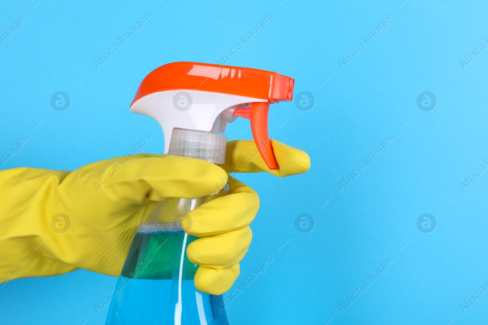 Photo of Woman holding plastic spray bottle on light blue background, closeup. Space for text