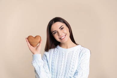 Photo of Portrait of young woman with wooden heart on color background