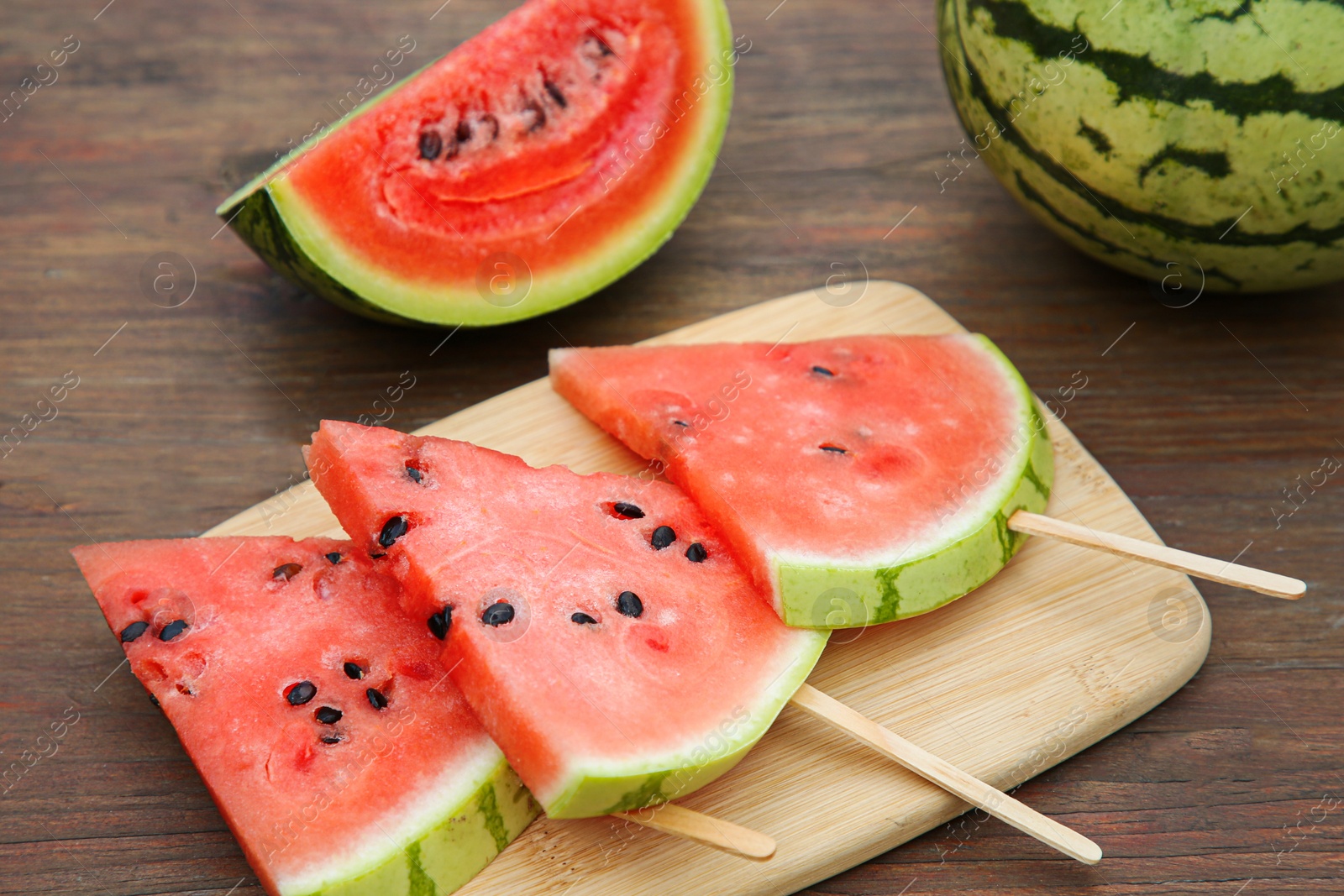 Photo of Whole and sliced delicious ripe watermelon on wooden table