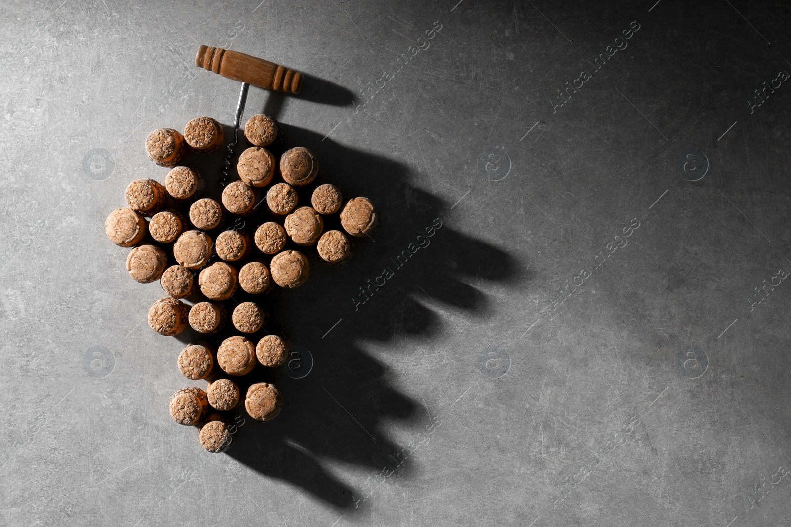 Photo of Grape made of wine bottle corks and corkscrew on grey table, top view. Space for text