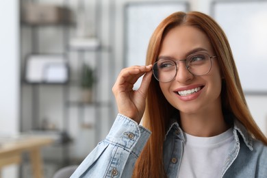 Portrait of beautiful smiling young woman. Happy lady with red hair at home. Space for text