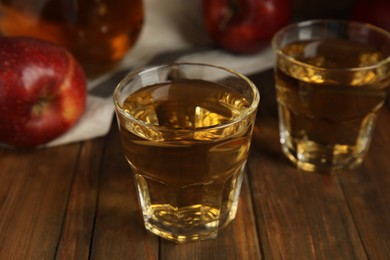 Photo of Glasses of delicious apple cider on wooden table