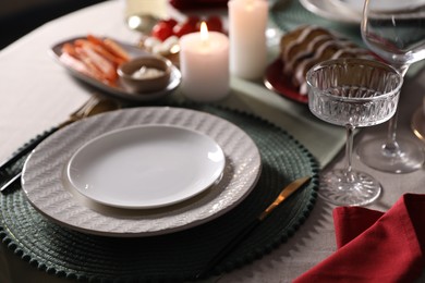 Table setting with burning candles, appetizers and dishware, closeup. Christmas celebration