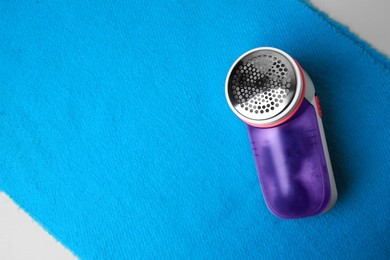 Modern fabric shaver on light blue cloth with lint, top view. Space for text