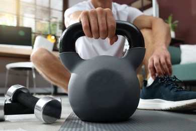 Photo of Man with kettlebell on floor at home, closeup