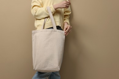 Woman with eco bag on beige background, closeup. Space for text