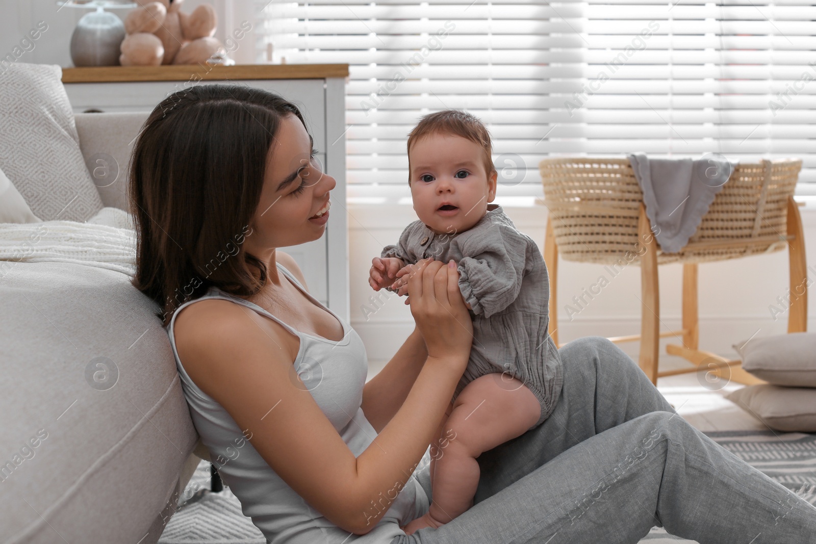 Photo of Young woman with her little baby on floor at home