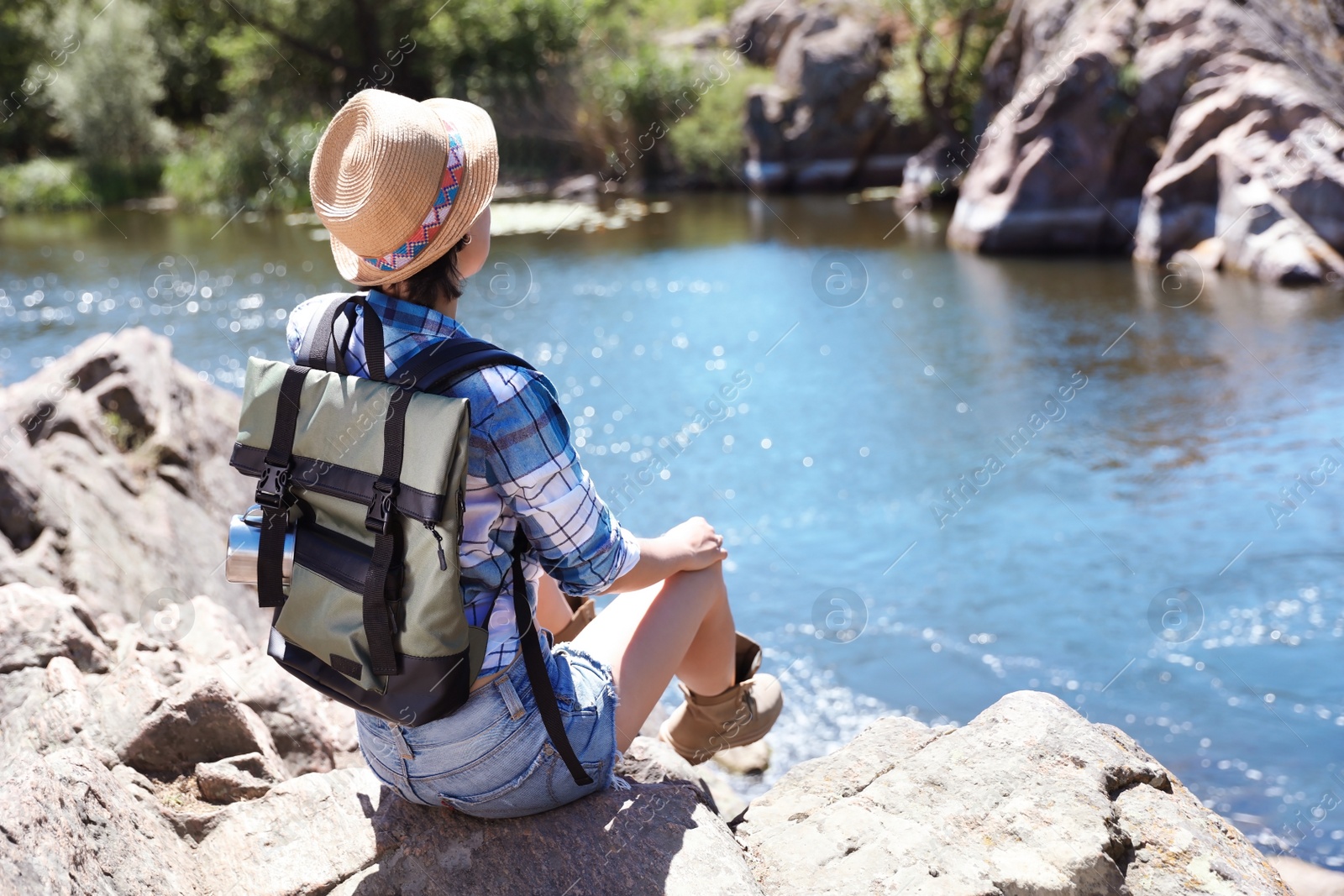 Photo of Young woman on rock near river. Summer camp