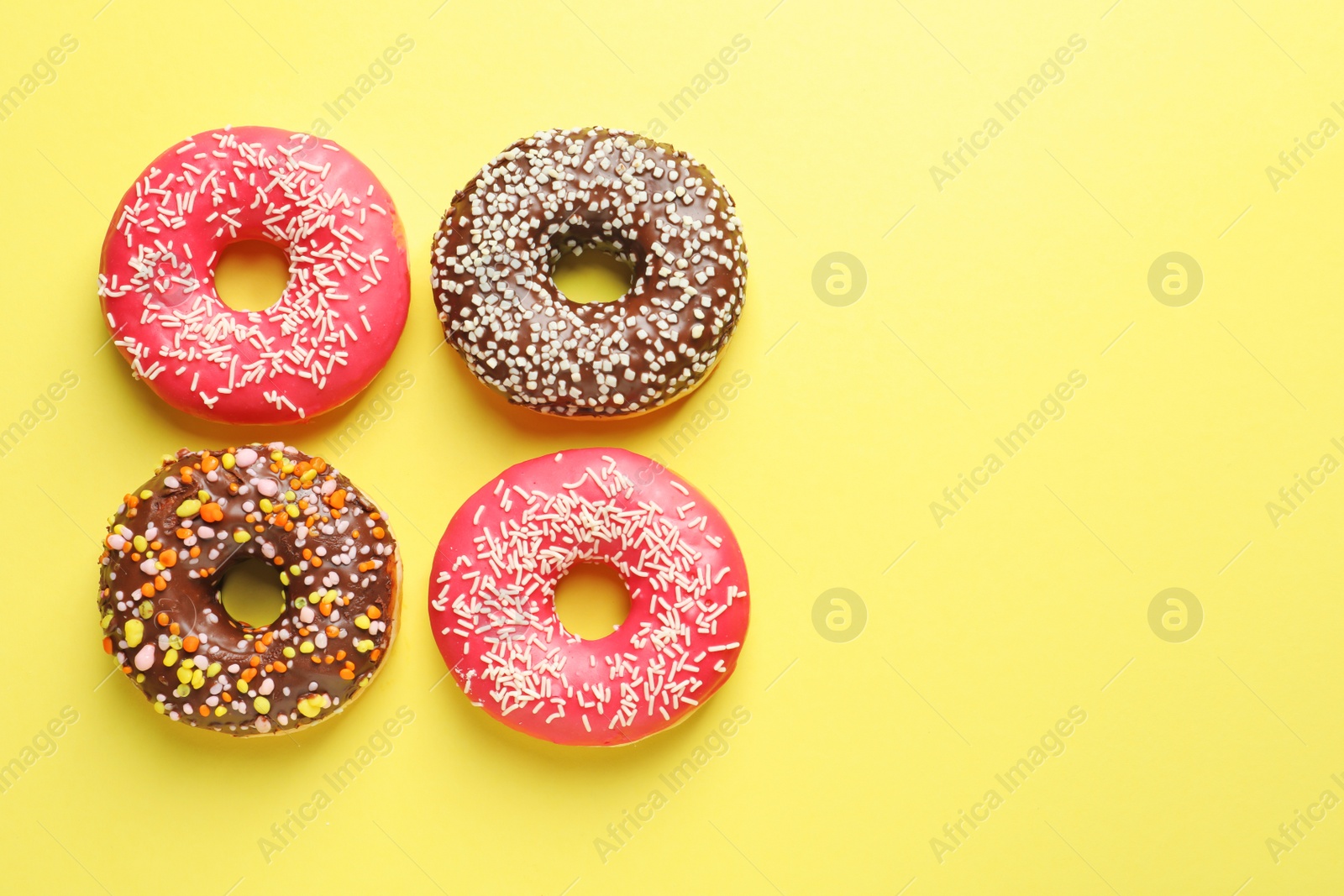 Photo of Delicious glazed doughnuts on color background, top view