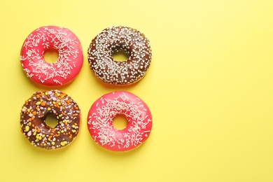 Delicious glazed doughnuts on color background, top view