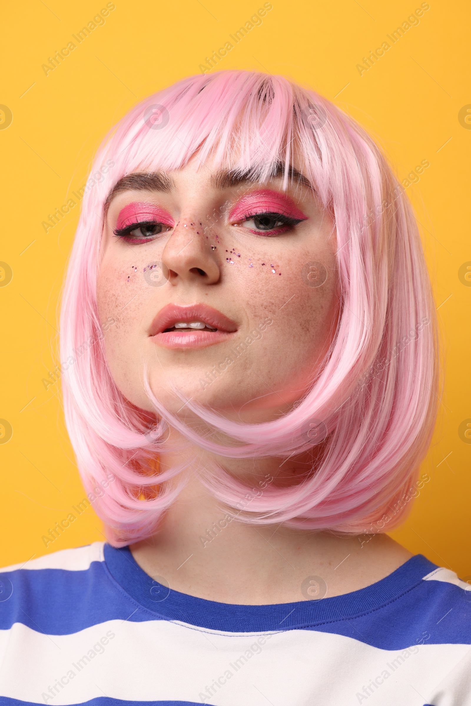 Photo of Beautiful woman with bright makeup and glitter freckles on yellow background