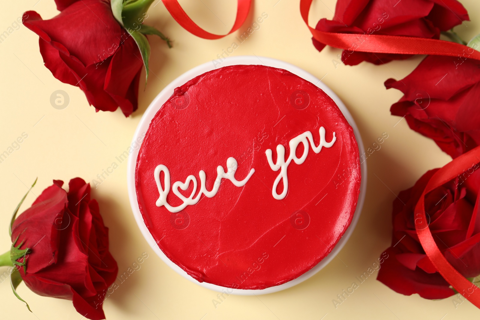 Photo of Bento cake with text Love You and red roses on beige table, top view. St. Valentine's day surprise