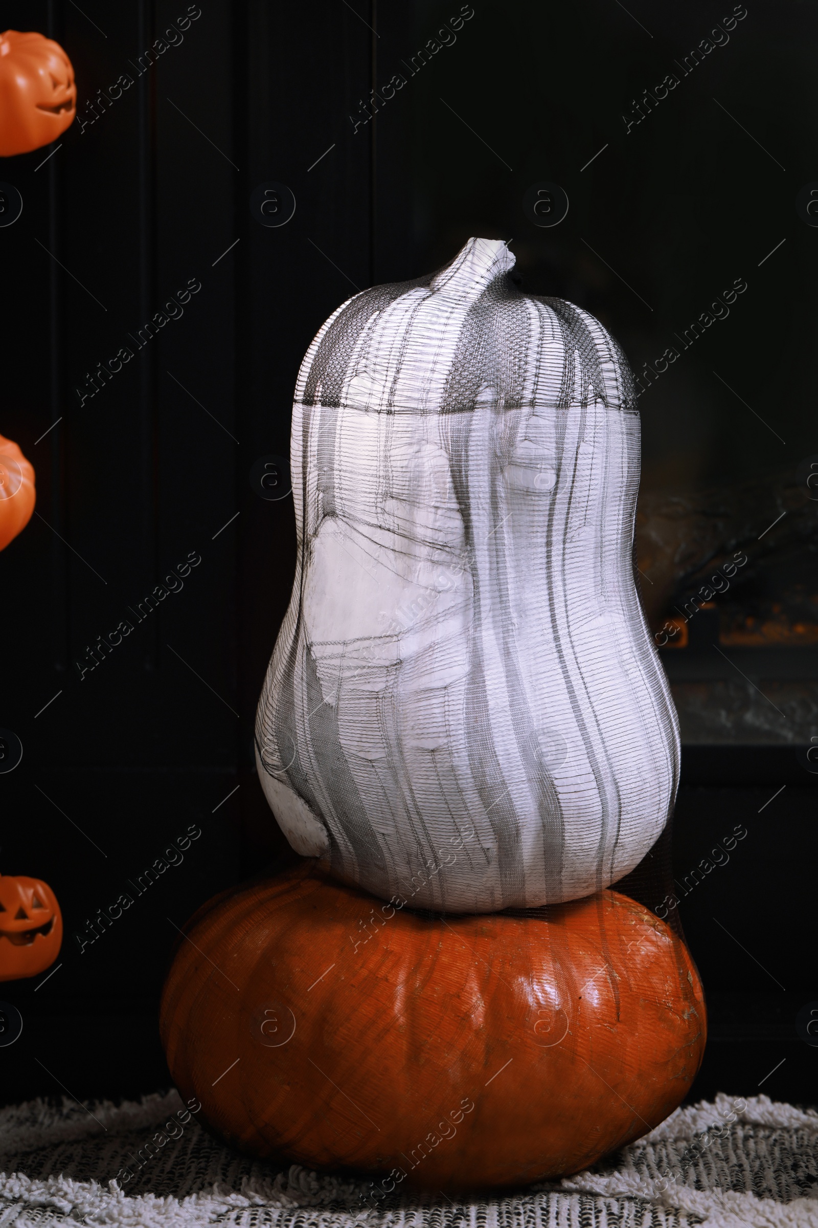 Photo of Colorful pumpkins on rug near fireplace. Halloween decorations