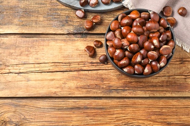 Photo of Fresh sweet edible chestnuts on wooden table, flat lay. Space for text