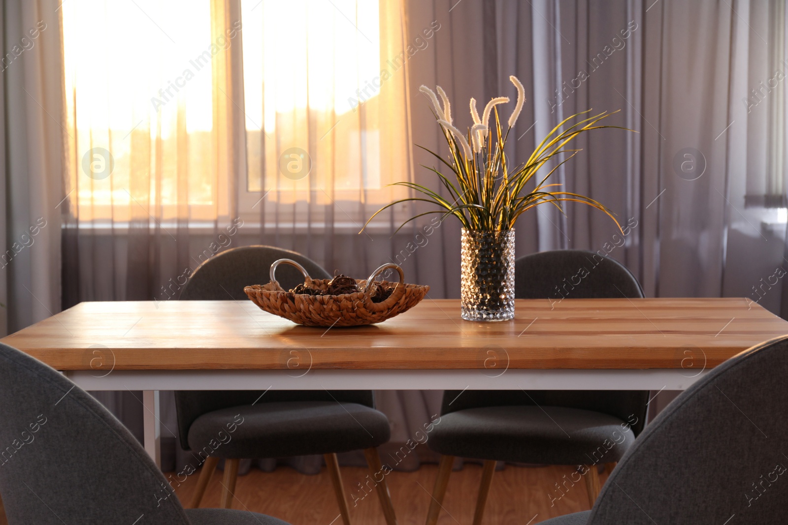 Photo of Vase on wooden table near window with curtains in room