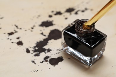 Inkwell with fountain pen on vintage parchment with ink stains, closeup