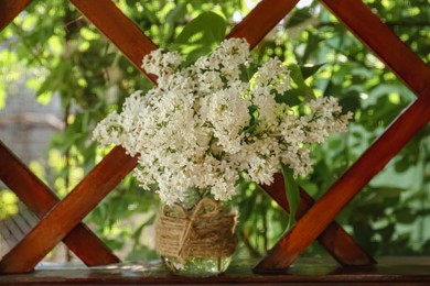 Photo of Beautiful lilac flowers in glass jar near window indoors