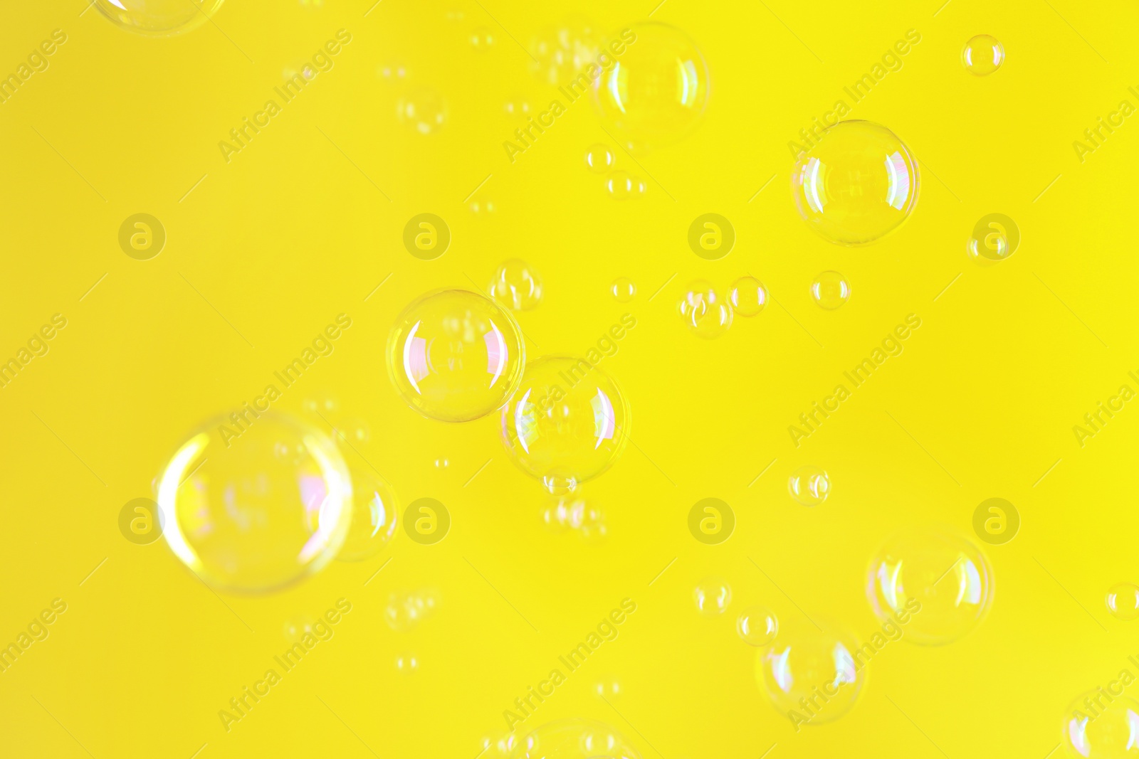 Photo of Beautiful transparent soap bubbles on yellow background