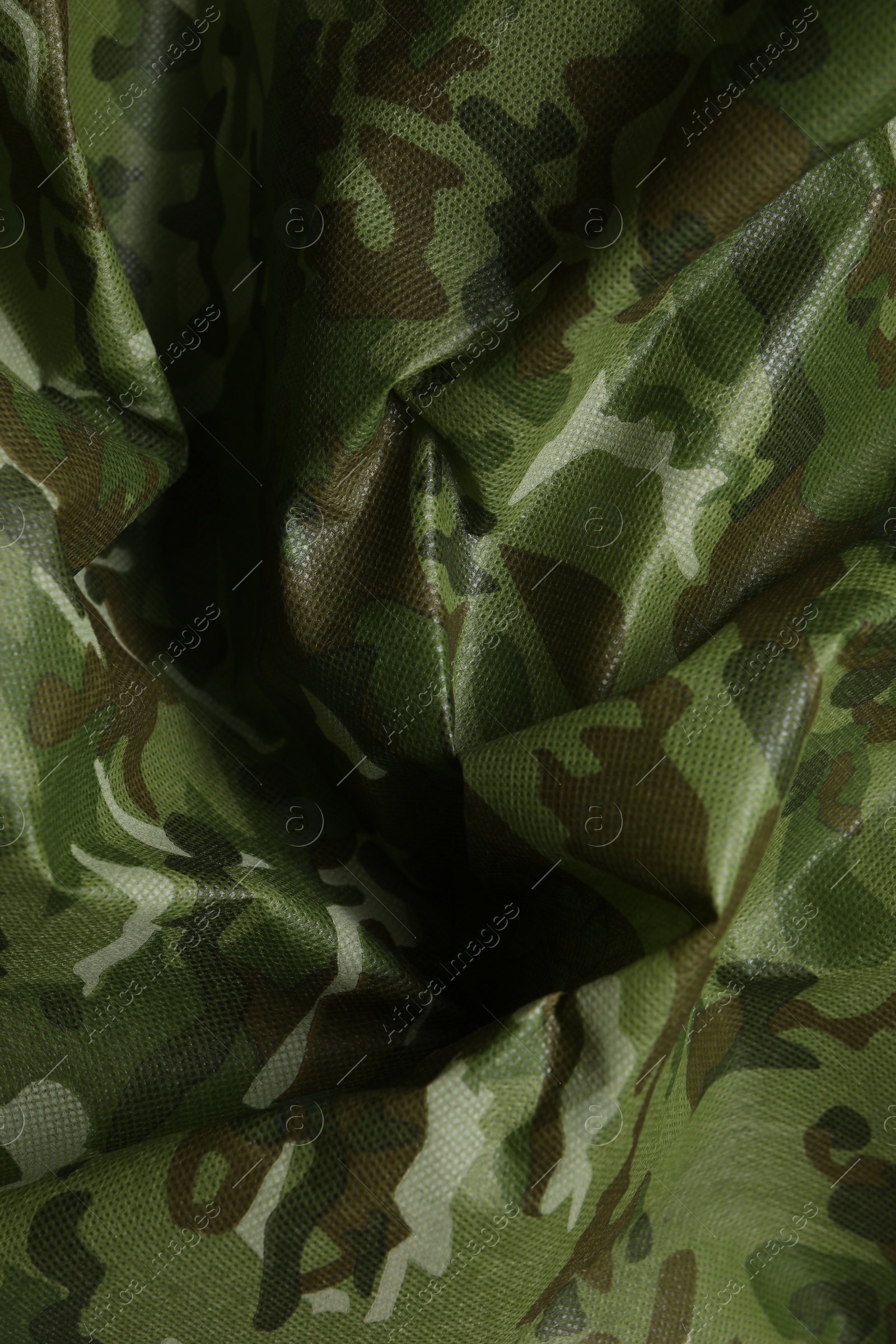 Photo of Texture of crumpled camouflage fabric as background, top view