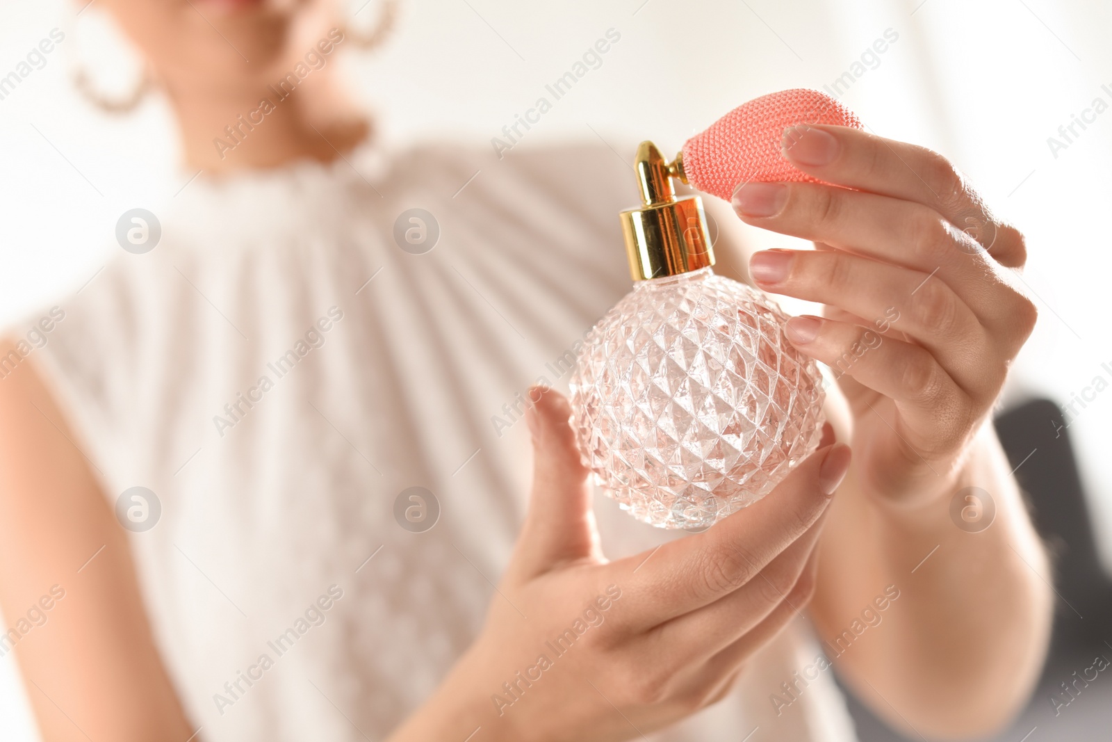 Photo of Young woman with bottle of perfume on blurred background, closeup