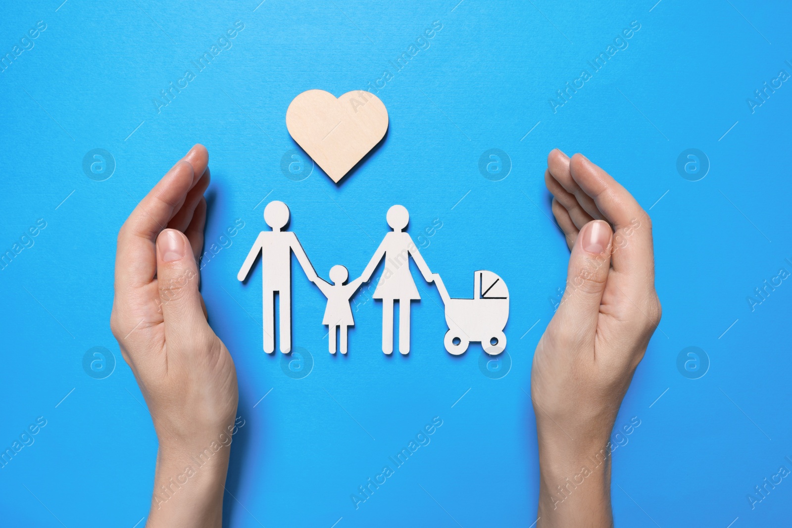 Photo of Woman protecting figures of family on light blue background, top view. Insurance concept