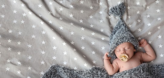 Image of Cute newborn baby in warm hat sleeping on bed, top view with space for text. Banner design
