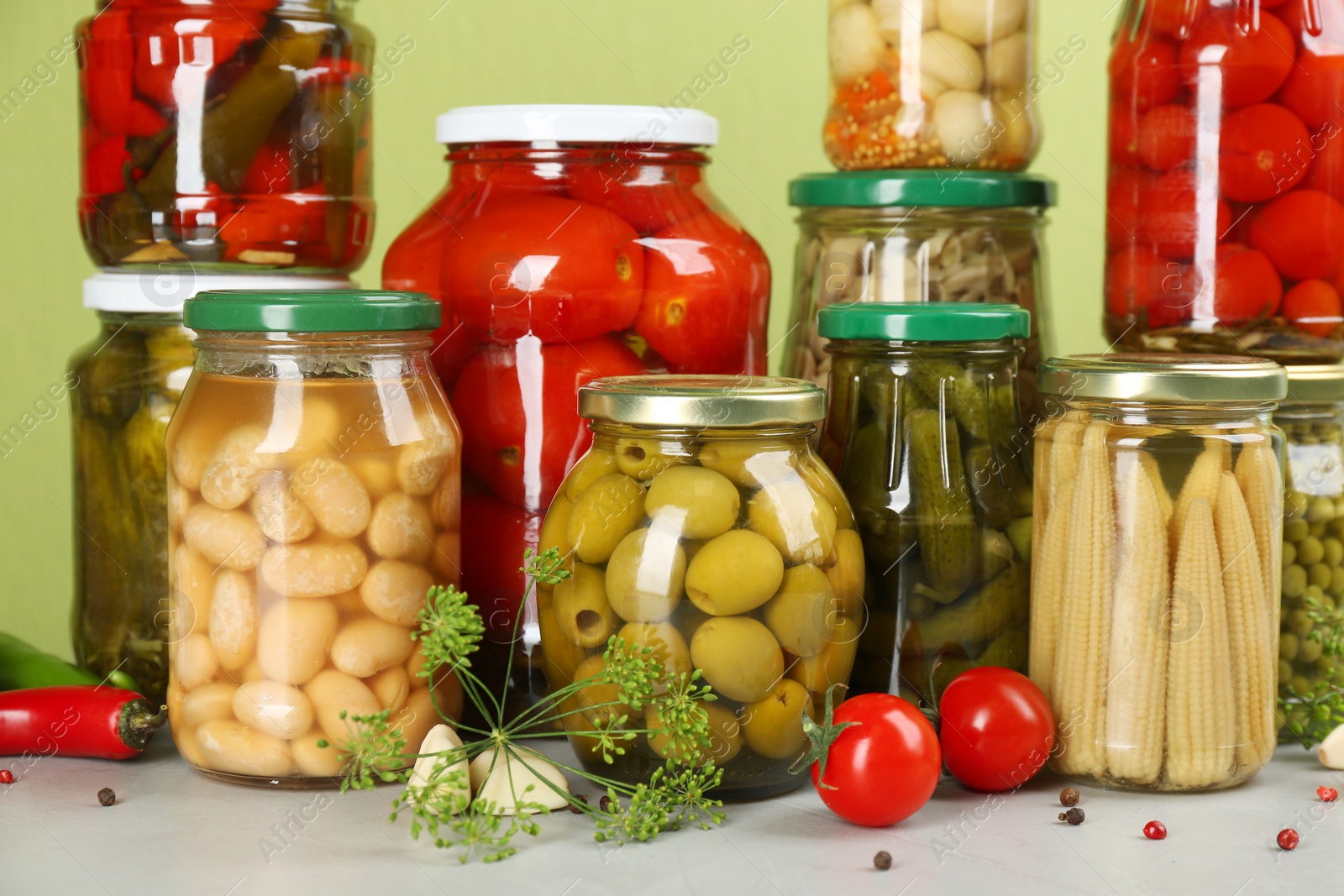 Photo of Jars of pickled vegetables and ingredients on light table