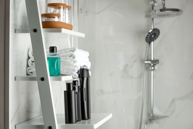 Photo of Stack of towels, shampoo and other toiletries on shelves near shower stall in bathroom, space for text