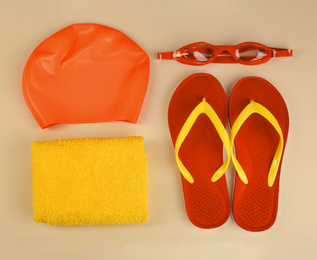 Flat lay composition with orange swimming accessories on beige background