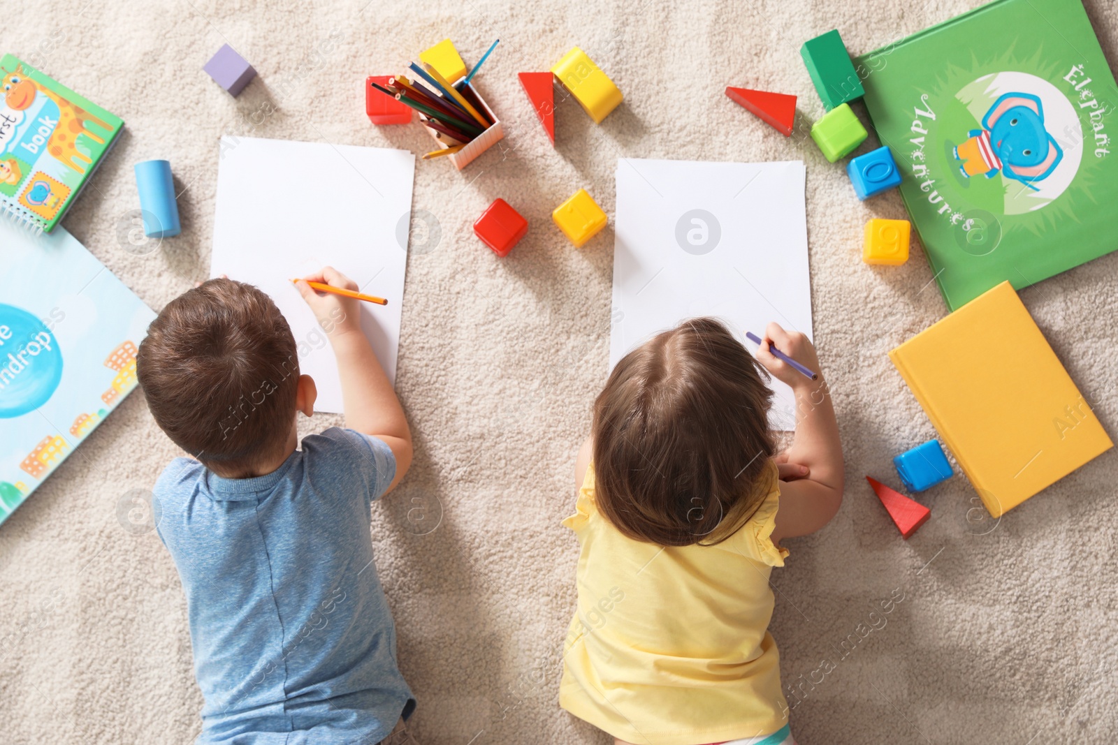 Photo of Little children drawing indoors, top view. Learning and playing