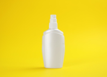 Bottle with insect repellent spray on yellow background