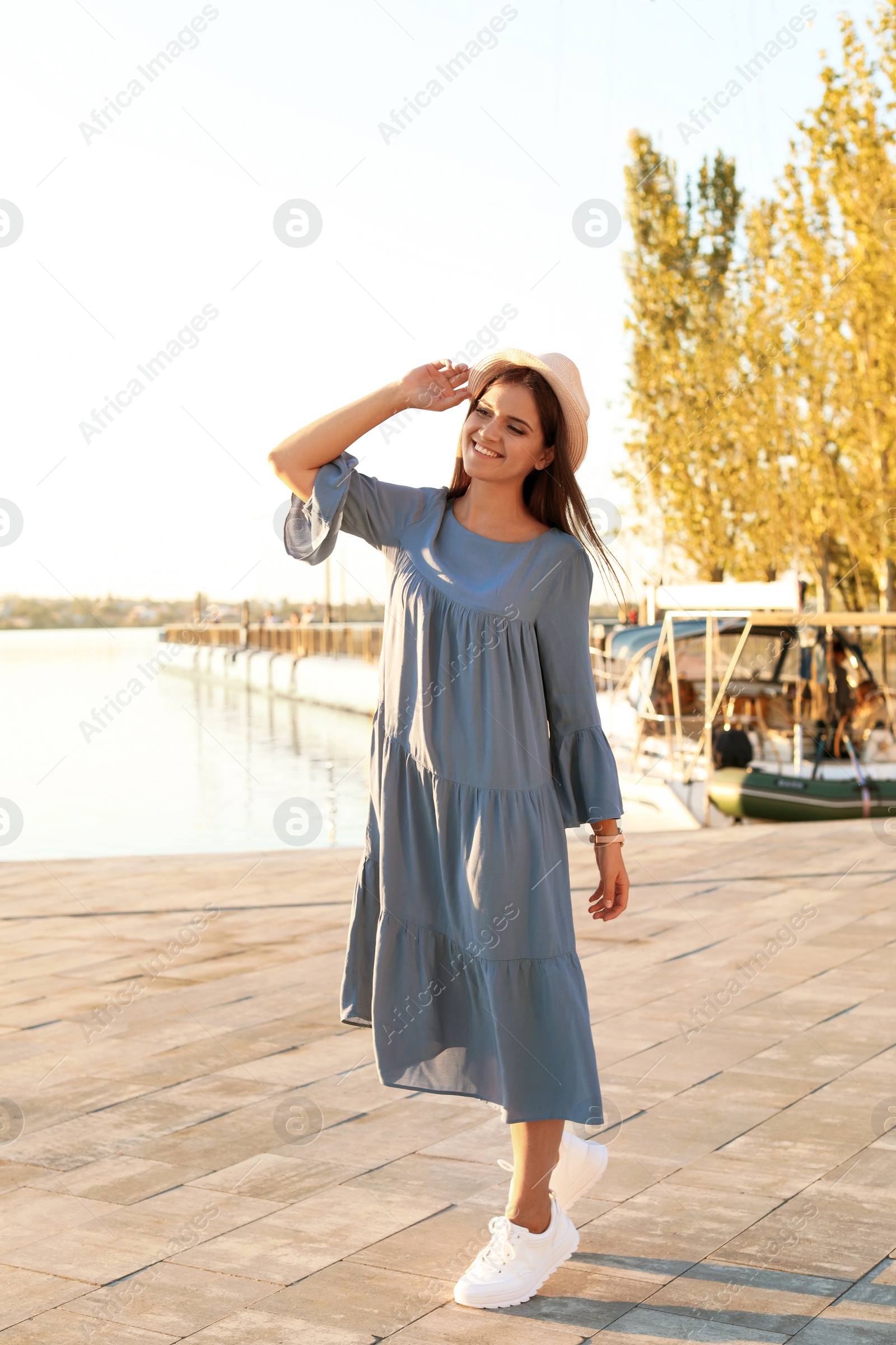 Photo of Young woman walking on pier at sunset light