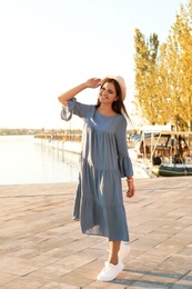 Photo of Young woman walking on pier at sunset light