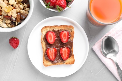 Photo of Flat lay composition of toast with chocolate spread and strawberries on light grey table. Healthy breakfast