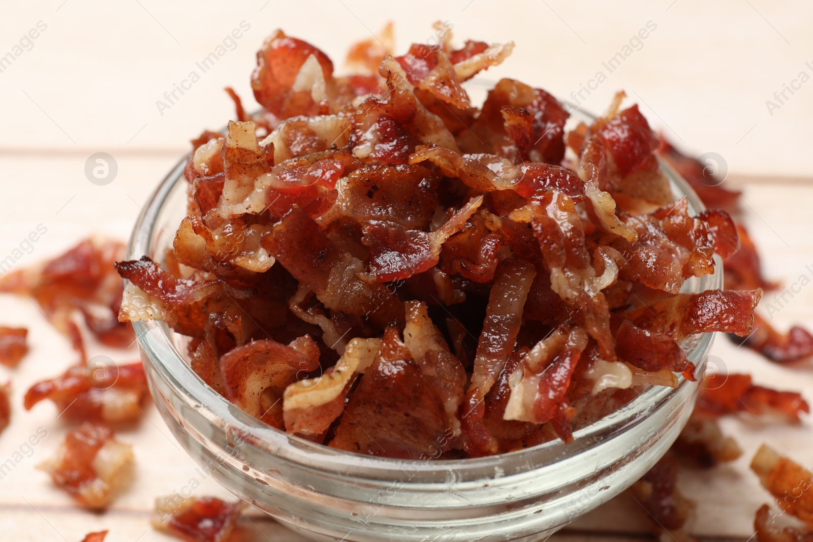 Photo of Pieces of tasty fried bacon in bowl on table, closeup