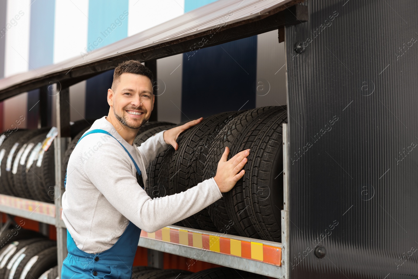 Photo of Mechanic near rack with car tires at service station