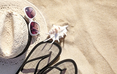 Flat lay composition with different beach accessories on sand. Space for text