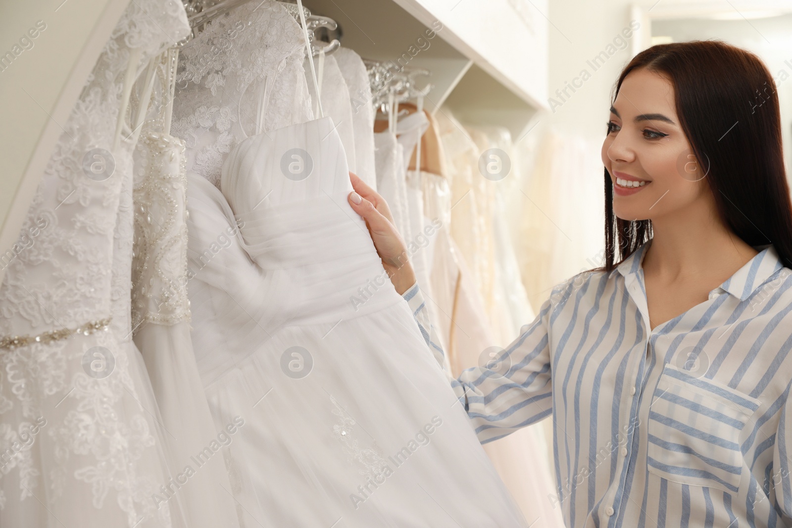 Photo of Young woman choosing wedding dress in salon