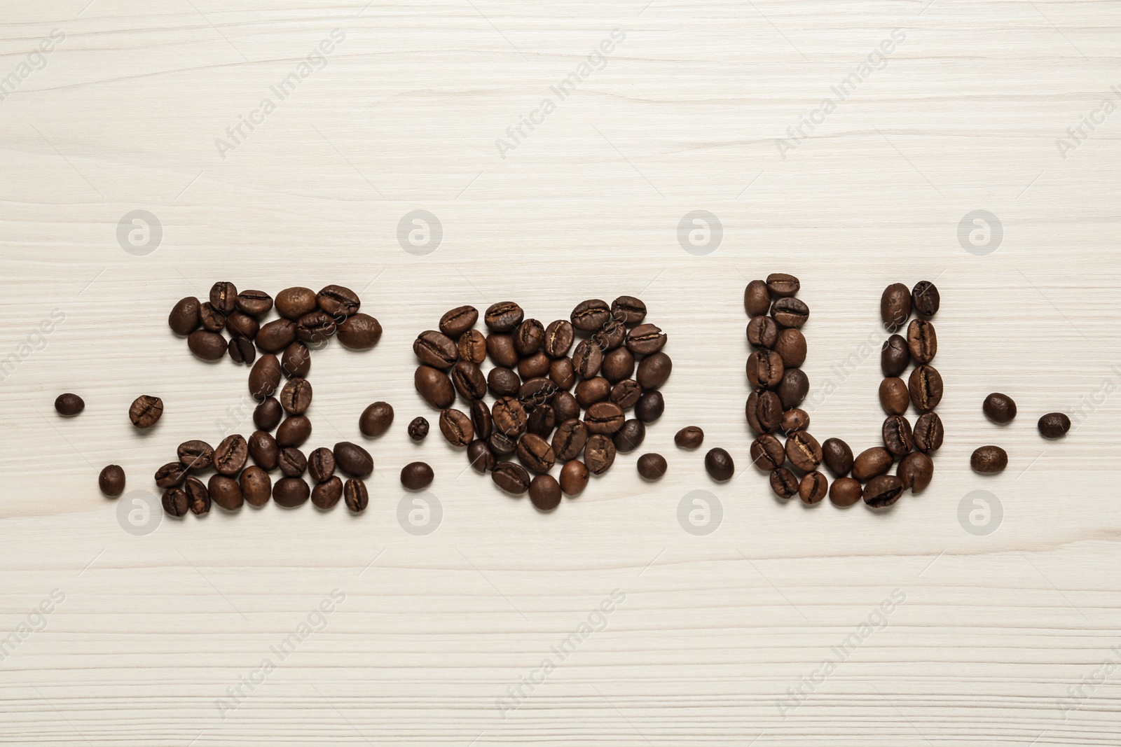 Photo of Phrase I Love You made of coffee beans on white wooden table, flat lay