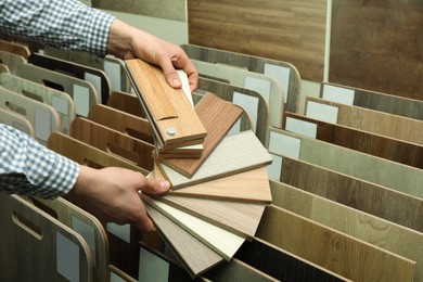 Man with samples of wooden flooring in shop, closeup