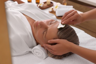 Woman receiving facial massage with jade gua sha tool in beauty salon, closeup