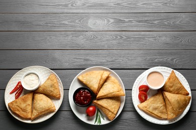 Fresh delicious crispy samosas served on grey wooden table, flat lay. Space for text