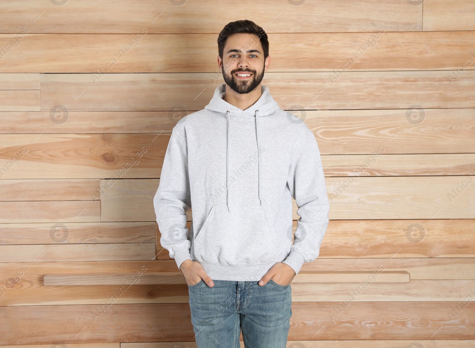 Photo of Portrait of young man in sweater at wooden wall. Mock up for design