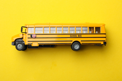 Photo of School bus on yellow background, top view. Transport for students